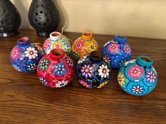 several colorful vases are sitting on a table together, one is painted with flowers