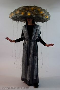 a woman in a black dress is wearing a cloud hat with lights on her head