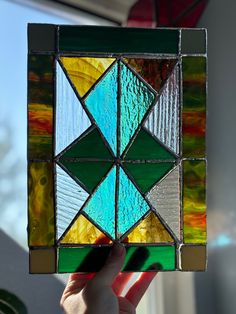 a hand holding up a stained glass piece