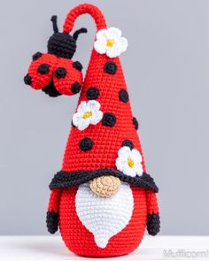 a crocheted red gnome hat with white flowers and ladybugs on it