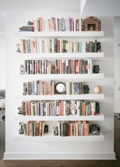 a bookshelf filled with lots of books on top of white shelves