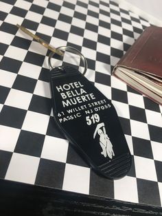 a hotel bell keychain sitting on top of a checkered table with a book