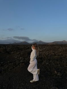 a woman standing on top of a rocky field