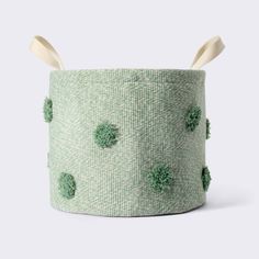 a green basket with pom poms on it