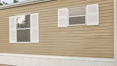 a brown house with white shutters on the front and side windows that are closed