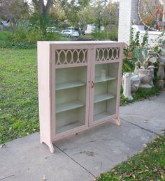 a pink cabinet sitting on top of a sidewalk next to a grass covered park area