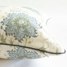 a close up of a decorative pillow on a white bed sheet with blue and green designs