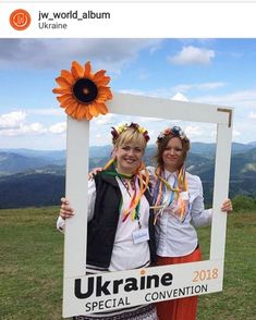 two women standing next to each other in front of a photo frame with a sunflower on it