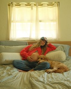 a woman sitting on a bed with her dog