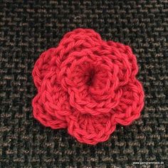 a crocheted red flower sitting on top of a carpet