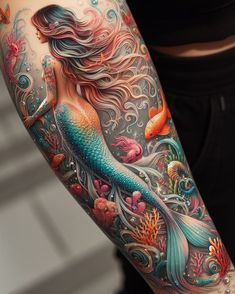 a woman's arm with a mermaid tattoo on it and an orange fish in the water