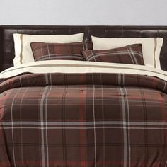 a bed with brown and white plaid comforter set on it's headboard