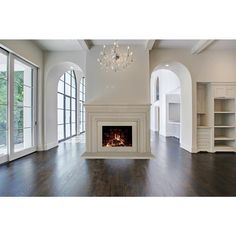 an empty living room with wood floors and chandelier