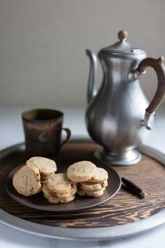 some cookies are on a plate next to a tea pot