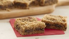 two pieces of granola bar sitting on top of a red napkin next to a cutting board