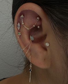 a woman's ear is adorned with different types of piercings and jewelry pieces