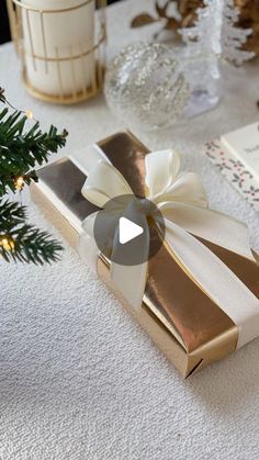 a christmas present sitting on top of a table next to a small tree and candles