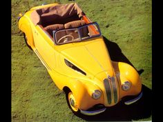 an old yellow car is parked in the grass