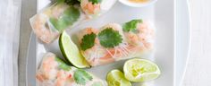 shrimp rolls with dipping sauce and cilantro on a white plate next to a napkin