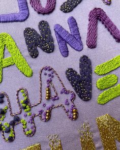 the letters and numbers are made up of different colors threaded together to make an embroidered wall hanging