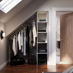 a closet with clothes hanging on the wall next to an open door and luggage bag