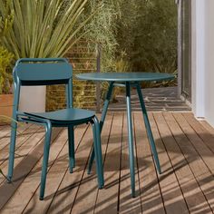 two blue chairs sitting on top of a wooden floor next to a table and chair