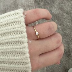 a woman's hand with a gold ring on her finger and a white sweater