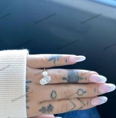 a woman's hand with tattoos and a diamond ring on her left thumb, in front of a car door