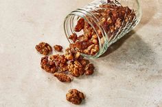 a glass jar filled with nuts sitting on top of a counter next to a pile of walnuts