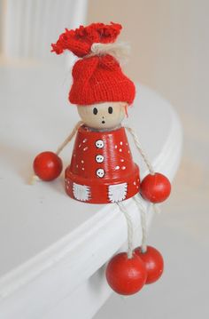 a small red doll is hanging on the edge of a white shelf with balls attached to it