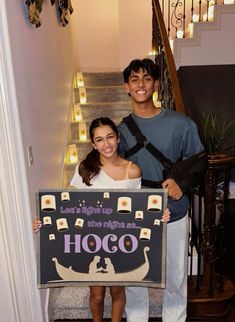 a man and woman standing on the stairs holding a sign that says harry potter is coming to hog