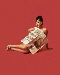 a woman is sitting on the floor reading a newspaper with her legs crossed and feet crossed