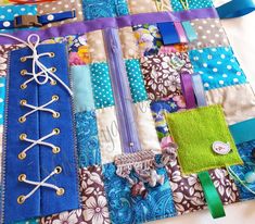 a close up of a patchwork quilt with various items attached to the fabric and ribbons