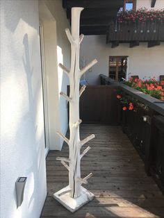 a tall white tree on top of a wooden floor next to a planter filled with flowers