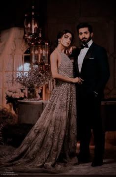 a man and woman standing next to each other in front of a chandelier