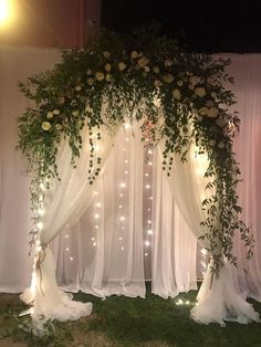 the wedding arch is decorated with flowers and greenery for an outdoor ceremony at night