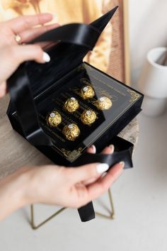 a person holding a box with four chocolates in it's packaging and one hand reaching into the package