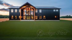 a large black house sitting on top of a lush green field