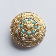 "Vintage round and domed shield brooch, scarf or lapel pin. Braided and textured circles of gold tone metal punctuated by faux turquoise and faux pearl beads. A very symmetric and striking piece for gifting or for a collection. Marked \"A737\". Roll over closure.  Measures 1 3/8\" diameter.  In good condition with no missing or broken beads. There is slight wear on the edge of the shield best seen in pictures 2 and 3 at the bottom. The pictures are part of the description.  Do browse our other items. We combine shipping for savings. International purchasers may wish to contact the shop for an accurate quote to the shipping address." Gold Round Costume Jewelry Brooches, Gold Round Enamel Brooch Pin, Gold Round Enamel Pin Brooch, Gold Round Enamel Pin, Brooch Scarf, 1960s Jewelry, Purple Pansy, Birthday Gifts For Grandma, Vintage Sapphire