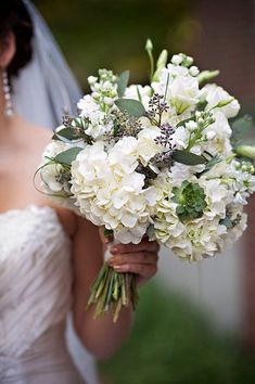 a bride holding a bouquet of white flowers