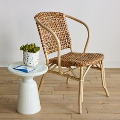 a wicker chair next to a small table with a potted plant on it