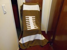 a crocheted football blanket sitting on top of a wooden floor next to a door