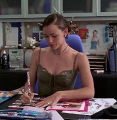 a woman sitting at a desk in an office writing on her clipboard and holding a pen