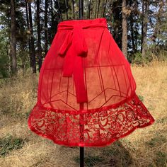 a red skirt on a stand in the grass with trees in the backgroud