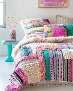 a bed covered in colorful blankets and pillows