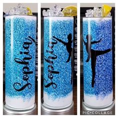 three tall glasses filled with blue glitter and one has a figure on the side, while the other is holding a lemon