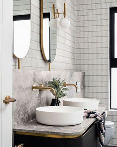 two white sinks in a bathroom with gold fixtures and marble counter tops on the vanity