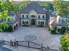 an aerial view of a large home with stone driveway and gated in area surrounded by trees