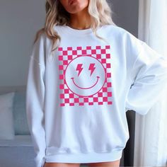 Spread joy and style with our Checkered Smiley Graphic T-Shirt or Sweatshirt! Featuring a playful checkered smiley face, this piece adds a fun twist to your casual wardrobe. Available as both a t-shirt and a sweatshirt, it's perfect for any season. The high-quality fabric ensures comfort and durability, while the unique design makes it a standout choice for everyday wear. Whether you're dressing up for a casual outing or lounging at home, this checkered smiley graphic piece is sure to bring a sm Casual Smiley Face T-shirt, Checkered Smiley Face, Smiley Shirt, Smiley Graphic, Pink Smiley, Smiley Face Shirt, Pink Checkered, Color Charts, Cute Tshirts