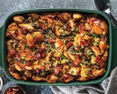 a green casserole dish with meat and vegetables in it on a gray surface